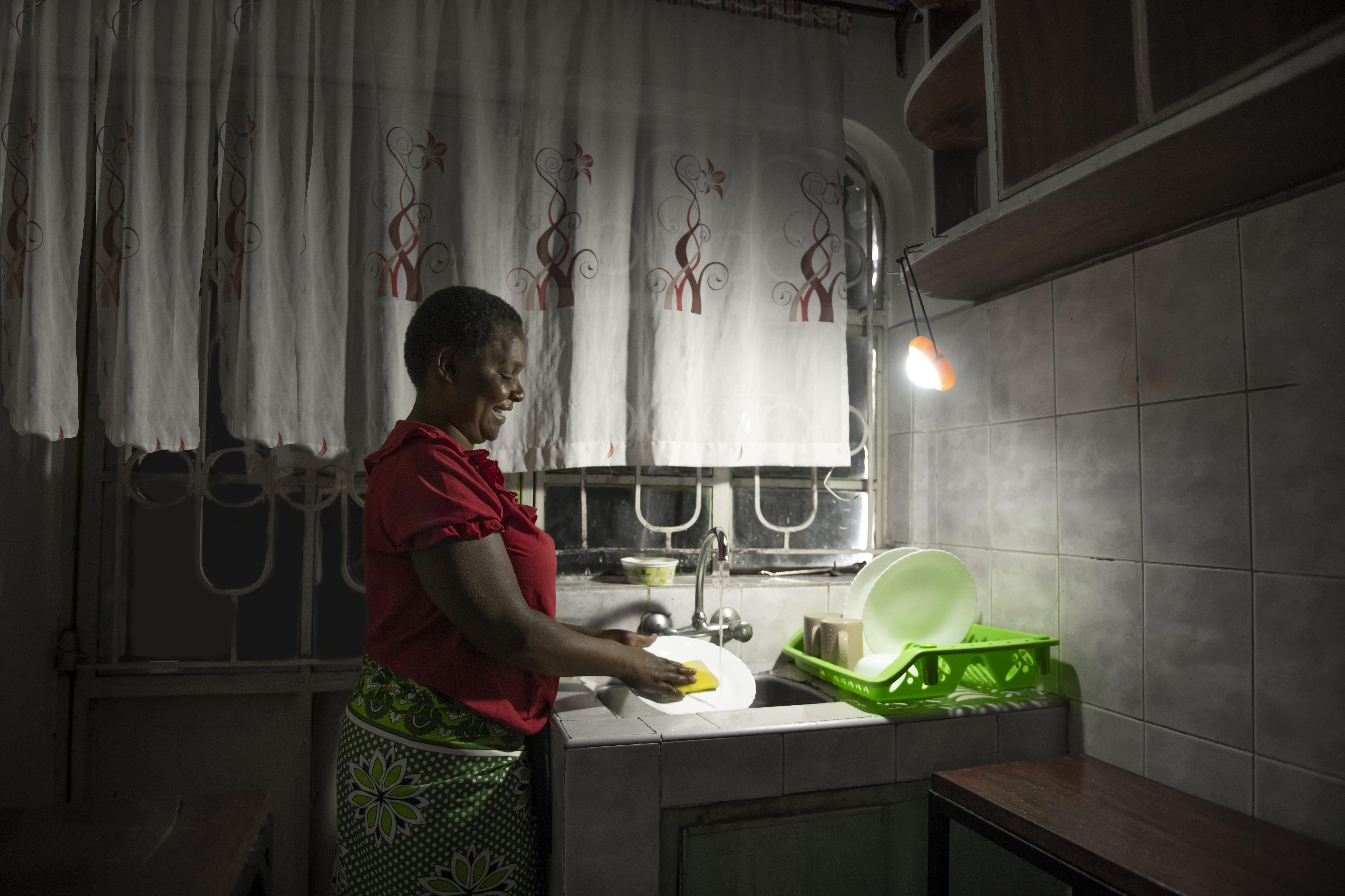 Woman uses her Sun King Pro 200 to light up the sink as she washes dishes.
